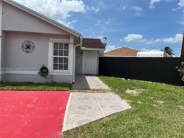 entrance to property with stucco siding, a yard, and fence