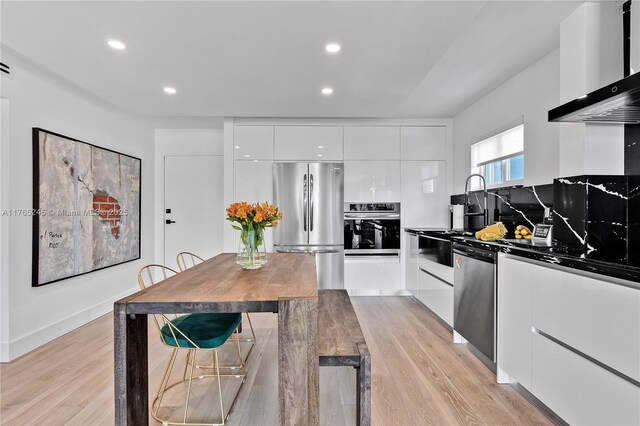 4000 NE 170th St Unit 300, North Miami Beach, FL 33160 - kitchen with light wood-type flooring, modern cabinets, appliances with stainless steel finishes, white cabinets, and wall chimney range hood