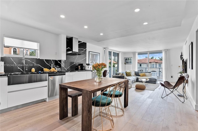 4000 NE 170th St Unit 300, North Miami Beach, FL 33160 - kitchen featuring dark countertops, light wood finished floors, wall chimney range hood, decorative backsplash, and stainless steel dishwasher