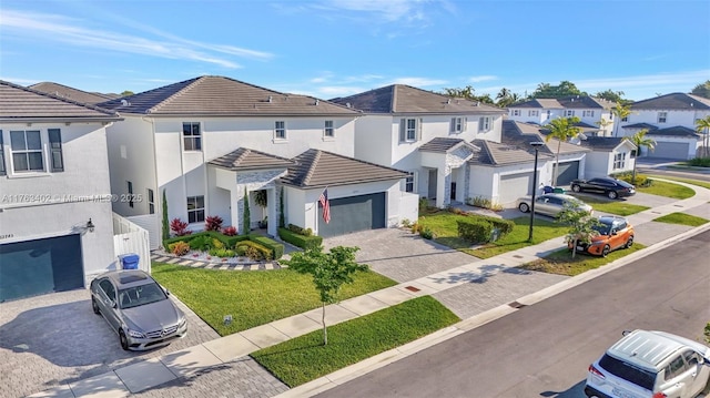 townhome / multi-family property with a residential view, a tile roof, stucco siding, a garage, and driveway