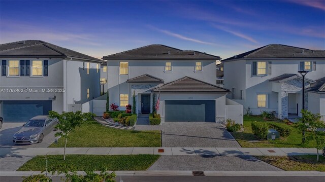 traditional home with stucco siding, a front lawn, a garage, a tile roof, and decorative driveway