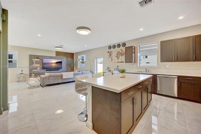 kitchen with visible vents, a kitchen island, open floor plan, light countertops, and stainless steel dishwasher