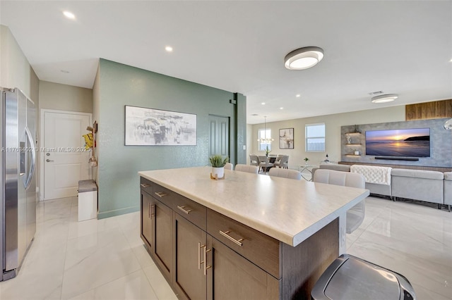 kitchen featuring a center island, open floor plan, stainless steel refrigerator with ice dispenser, and light countertops