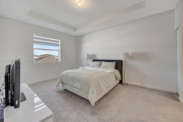 bedroom featuring a raised ceiling, baseboards, and carpet floors
