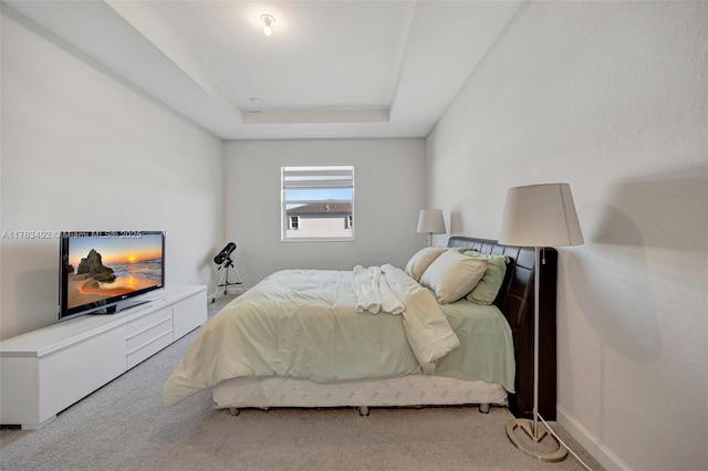 bedroom featuring baseboards, a raised ceiling, and carpet