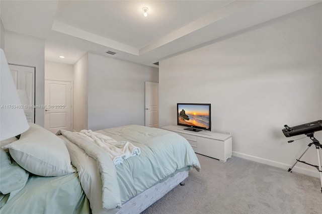 bedroom with light carpet, visible vents, baseboards, and a tray ceiling