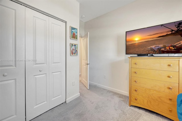 unfurnished bedroom featuring lofted ceiling, baseboards, a closet, and light carpet