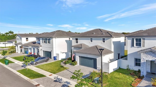 view of front of house featuring a front lawn, fence, a residential view, stucco siding, and decorative driveway