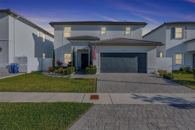view of front of house with a yard, an attached garage, stucco siding, a tile roof, and decorative driveway