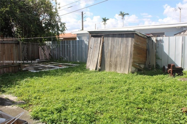 view of yard with an outbuilding, a fenced backyard, and a storage shed