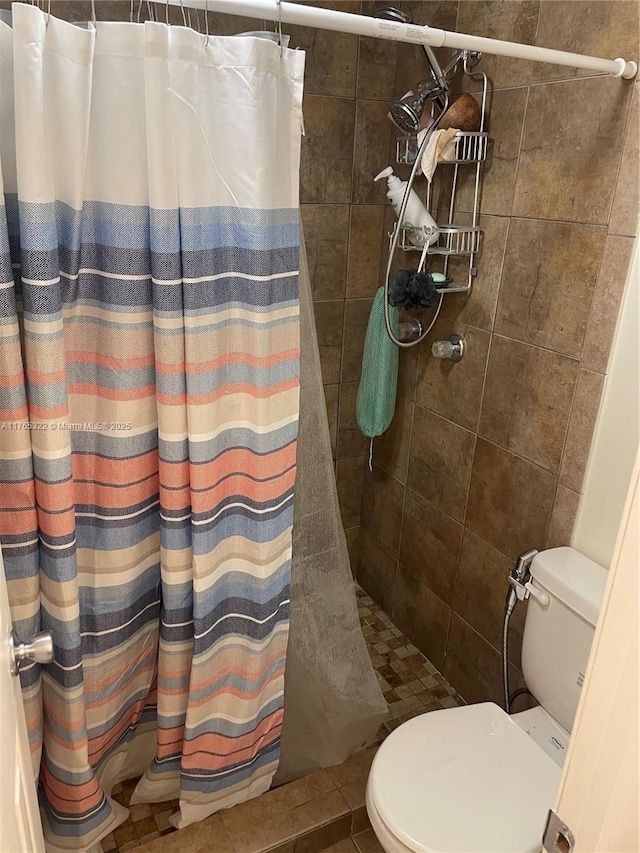 bathroom with tile patterned floors, toilet, and tiled shower