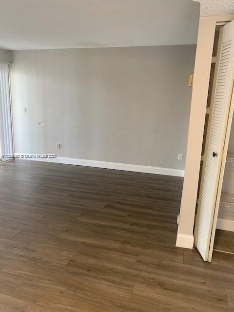 spare room with dark wood finished floors, baseboards, and a textured ceiling