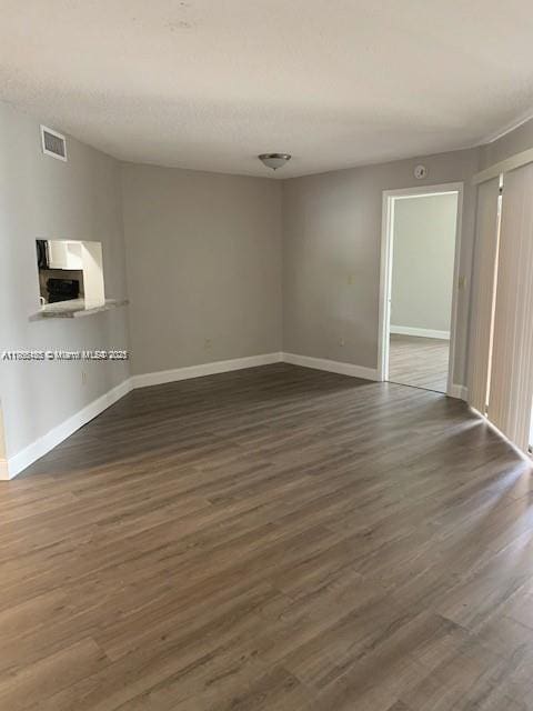 spare room with visible vents, baseboards, and dark wood finished floors