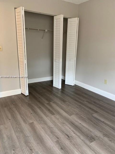 unfurnished bedroom with baseboards, two closets, and wood finished floors