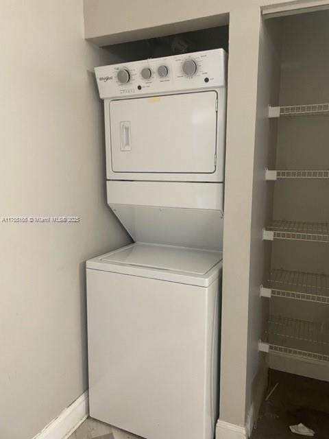 laundry room with laundry area, baseboards, and stacked washing maching and dryer