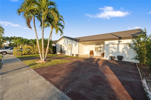 view of front of home with a tiled roof, a garage, stucco siding, and aphalt driveway