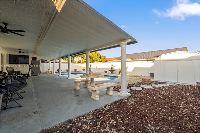 view of patio with a fenced backyard, a fenced in pool, a ceiling fan, a storage shed, and an outbuilding