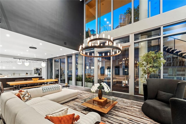 living area with a notable chandelier, recessed lighting, visible vents, and a towering ceiling