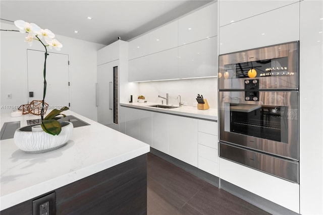 kitchen with a sink, light countertops, white cabinetry, stainless steel oven, and modern cabinets