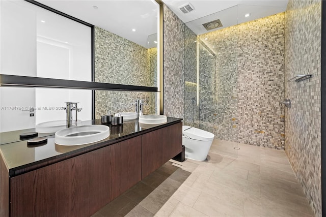 bathroom with tile walls, toilet, visible vents, and a sink