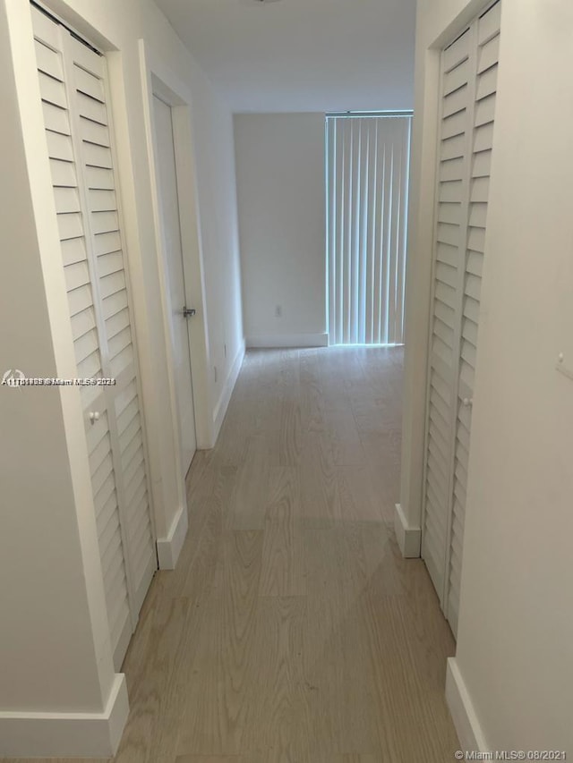 hall featuring baseboards and light wood-style floors