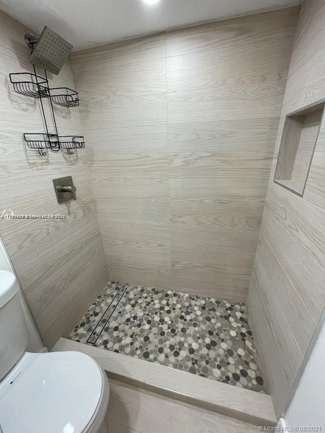 bathroom featuring tiled shower and toilet
