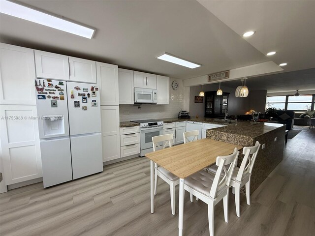 kitchen with white appliances, white cabinets, a peninsula, and light wood-style floors