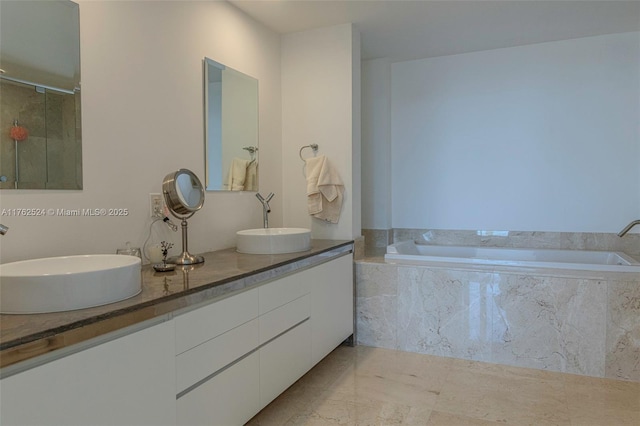 bathroom with double vanity, marble finish floor, a garden tub, and a sink
