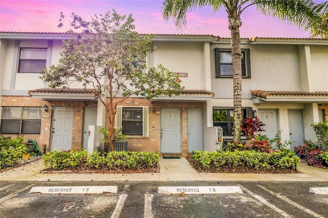 townhome / multi-family property featuring stucco siding, uncovered parking, and a tiled roof