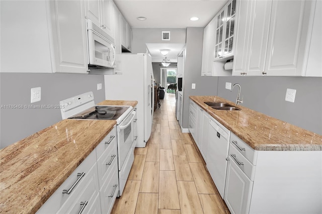 kitchen featuring a sink, visible vents, white appliances, and white cabinets