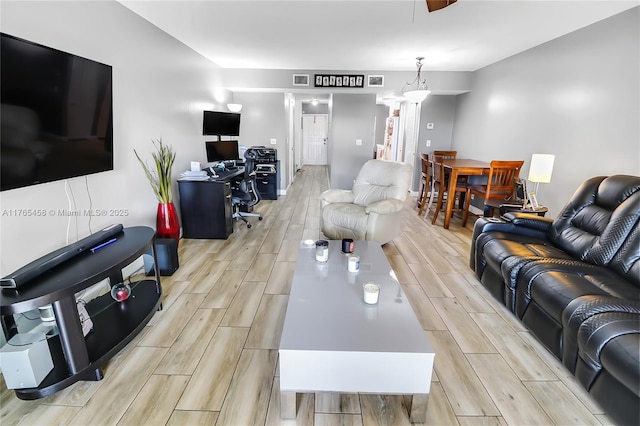living room featuring visible vents, ornate columns, and wood tiled floor