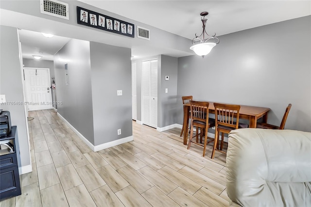 dining space with wood finish floors, visible vents, and baseboards