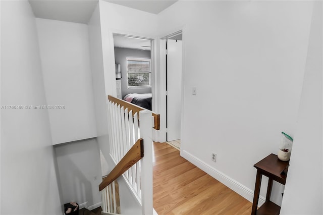 hallway with light wood finished floors, an upstairs landing, and baseboards