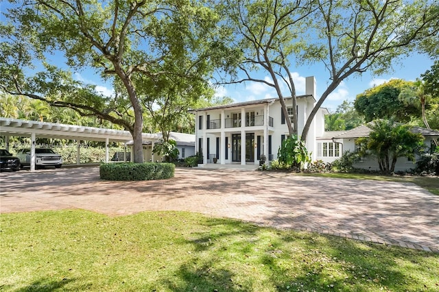 4550 Sunset Dr, Coral Gables, FL 33143 - rear view of house featuring a yard, stucco siding, a balcony, and a chimney