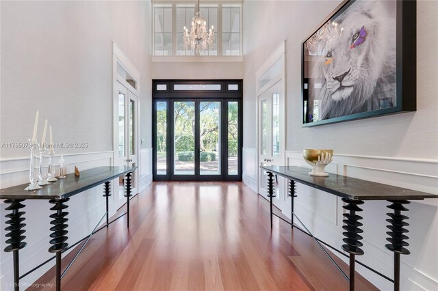 4550 Sunset Dr, Coral Gables, FL 33143 - entryway featuring wood finished floors, a high ceiling, wainscoting, and a chandelier