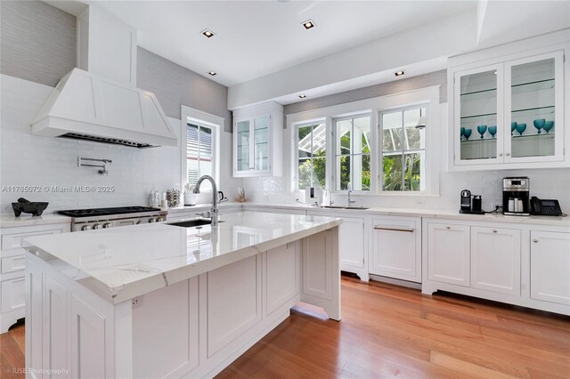 4550 Sunset Dr, Coral Gables, FL 33143 - kitchen featuring a sink, tasteful backsplash, a center island with sink, glass insert cabinets, and recessed lighting