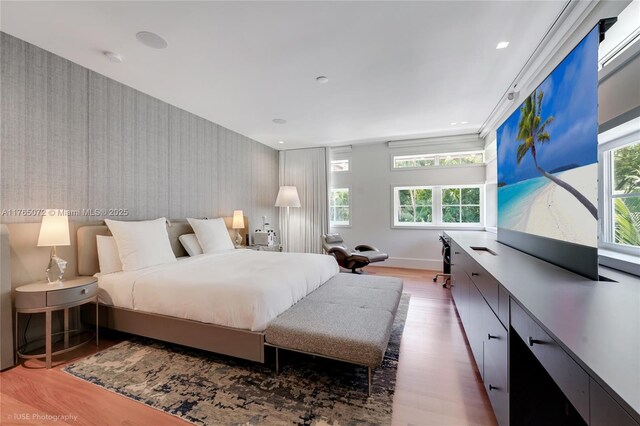 4550 Sunset Dr, Coral Gables, FL 33143 - bedroom with wallpapered walls, multiple windows, wood finished floors, an accent wall, and recessed lighting