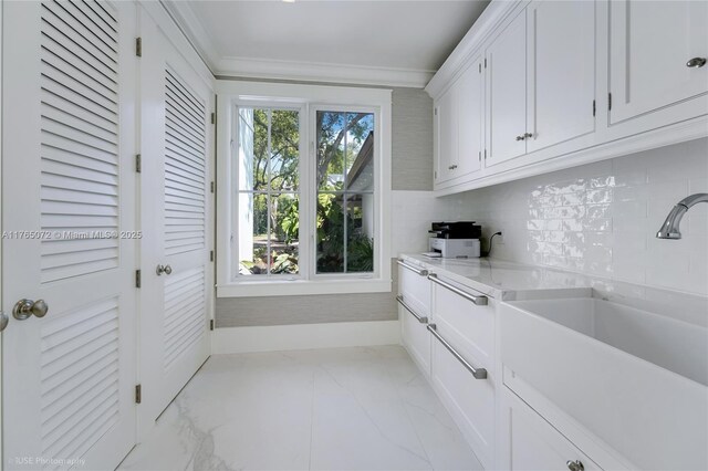 4550 Sunset Dr, Coral Gables, FL 33143 - kitchen featuring a sink, light marble finish flooring, white cabinetry, decorative backsplash, and crown molding