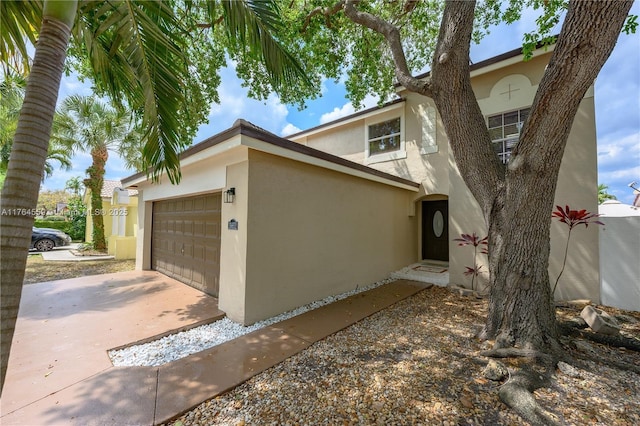 view of side of home featuring concrete driveway, stucco siding, and a garage