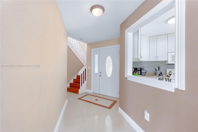 entrance foyer with stairway, baseboards, and light tile patterned floors