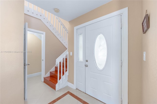 foyer with light tile patterned floors, stairway, and baseboards