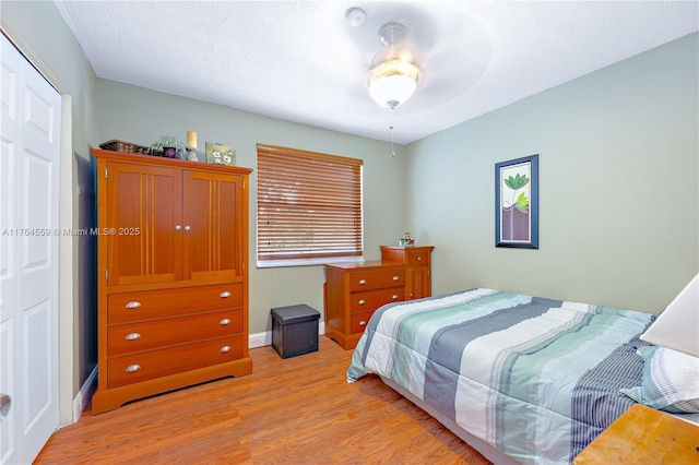 bedroom with light wood-style flooring, baseboards, and ceiling fan