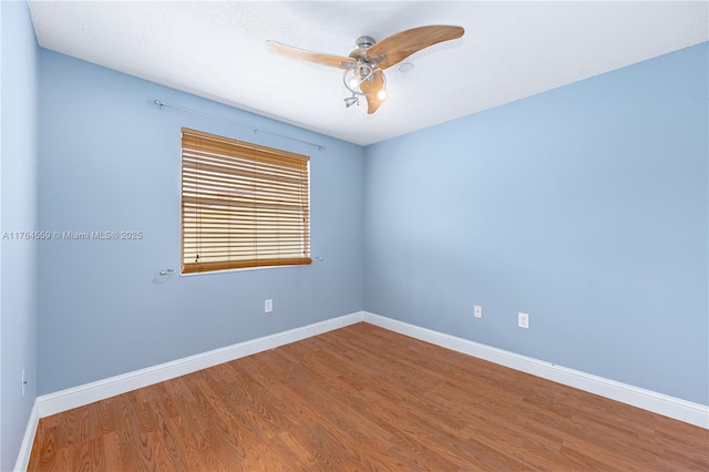 empty room featuring wood finished floors, baseboards, and a ceiling fan