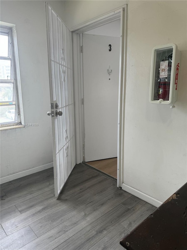 hall with baseboards and wood finished floors