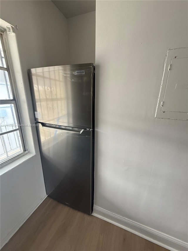 kitchen with electric panel, baseboards, wood finished floors, and freestanding refrigerator