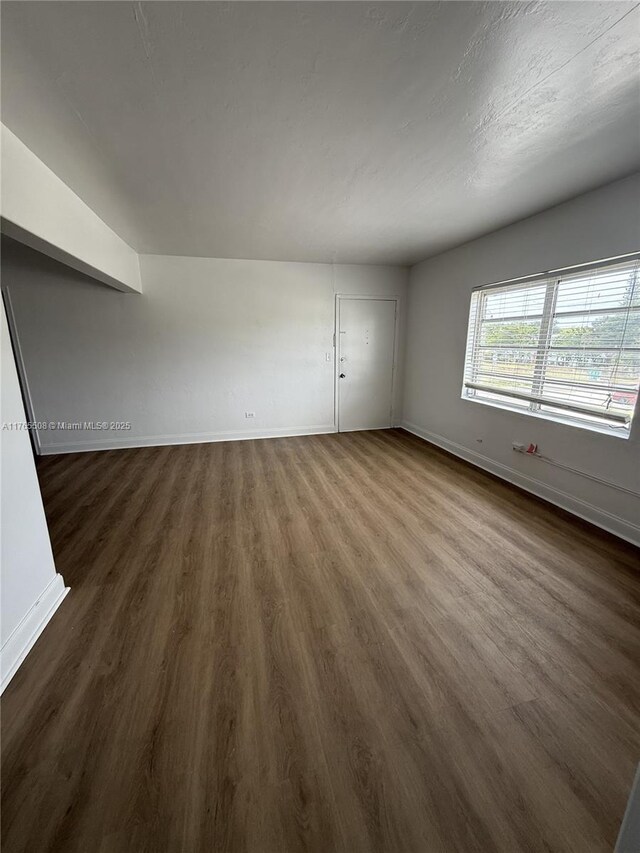 unfurnished room with dark wood-style floors and baseboards