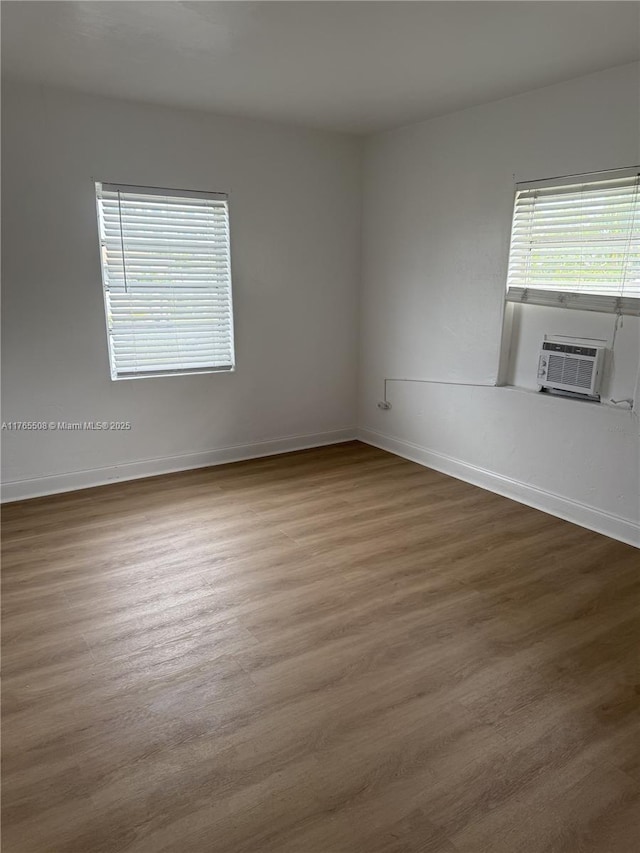 spare room with baseboards, cooling unit, and wood finished floors