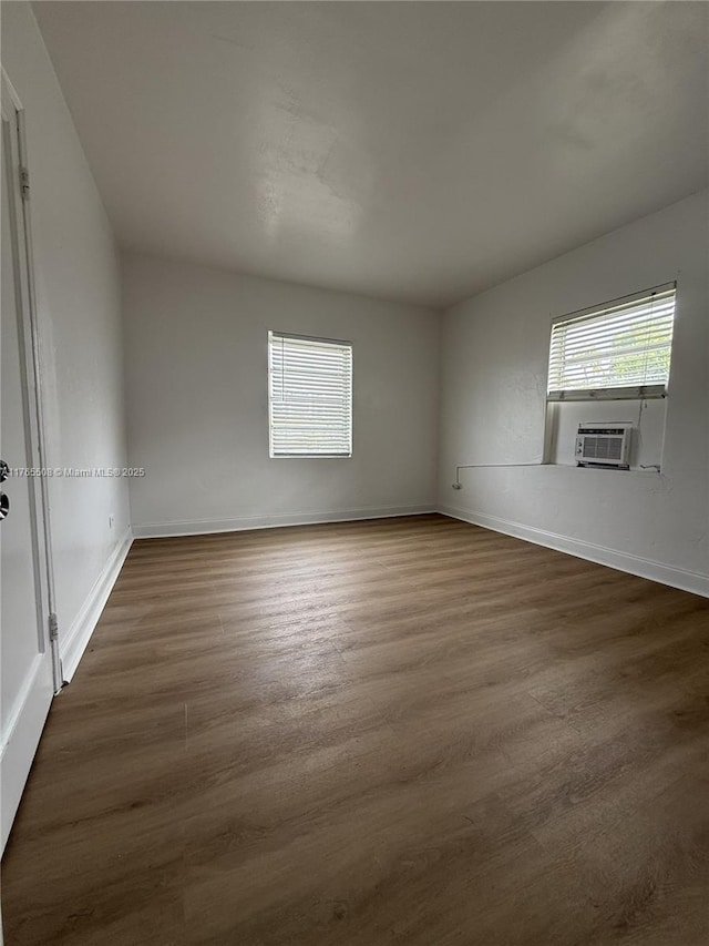 unfurnished room featuring dark wood-style floors, cooling unit, and baseboards