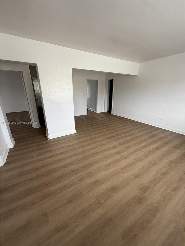 spare room with baseboards and wood finished floors