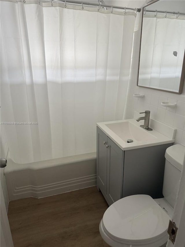 bathroom featuring toilet, vanity, shower / tub combo, and wood finished floors